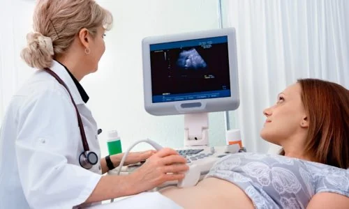 A doctor scanning a patient at an ultrasound machine, with the patient watching the screen.